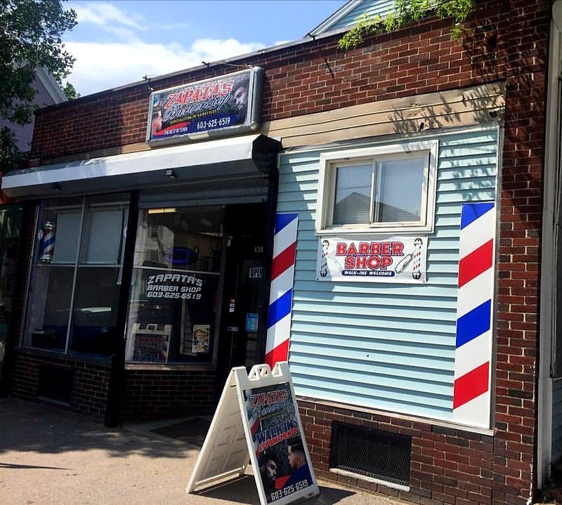Fachada de ladrillo de Zapata’s Barber Shop con postes tradicionales de barbería